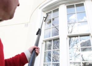 Professional using a water fed pole to clean high residential windows