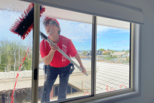 Window cleaner washing the exterior of a residential window in Brisbane